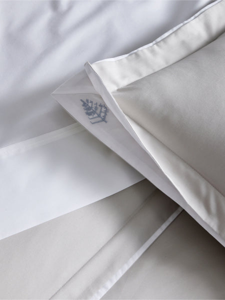 Willow Duvet Cover Set in Turkish Silver and Signature White. The image partially shows a pillow on a sheet, with the soft tones of the bedding set reflecting elegance and simplicity.